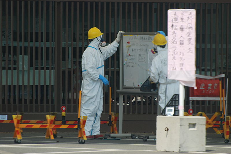 Des gardes en combinaison de radioprotection devant  l'entrée principale de la centrale de Fukushima 1 -Photo S. Herman