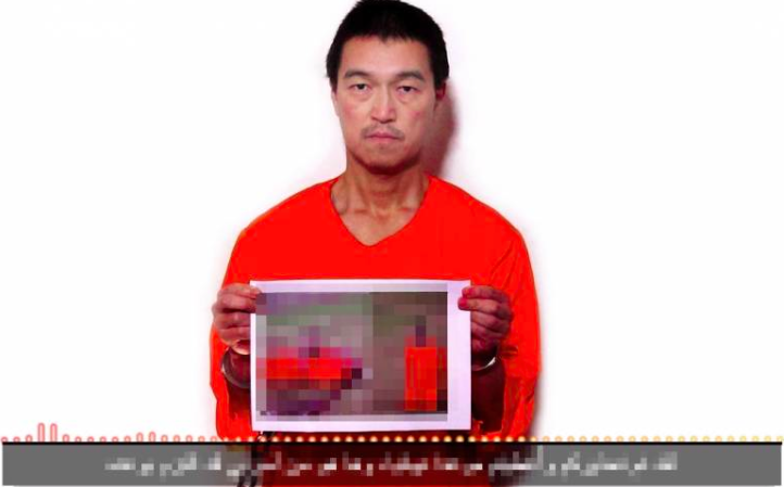 Image extraite de la vidéo montrant Kenji Goto avec une photo du corps de son compatriote.