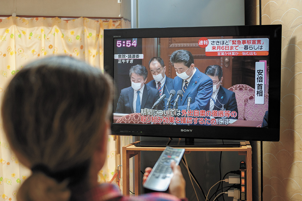 Femme regardant la télévision japonaise qui annonce l'état d'urgence par le Premier ministre du Japon face au Covid-19 